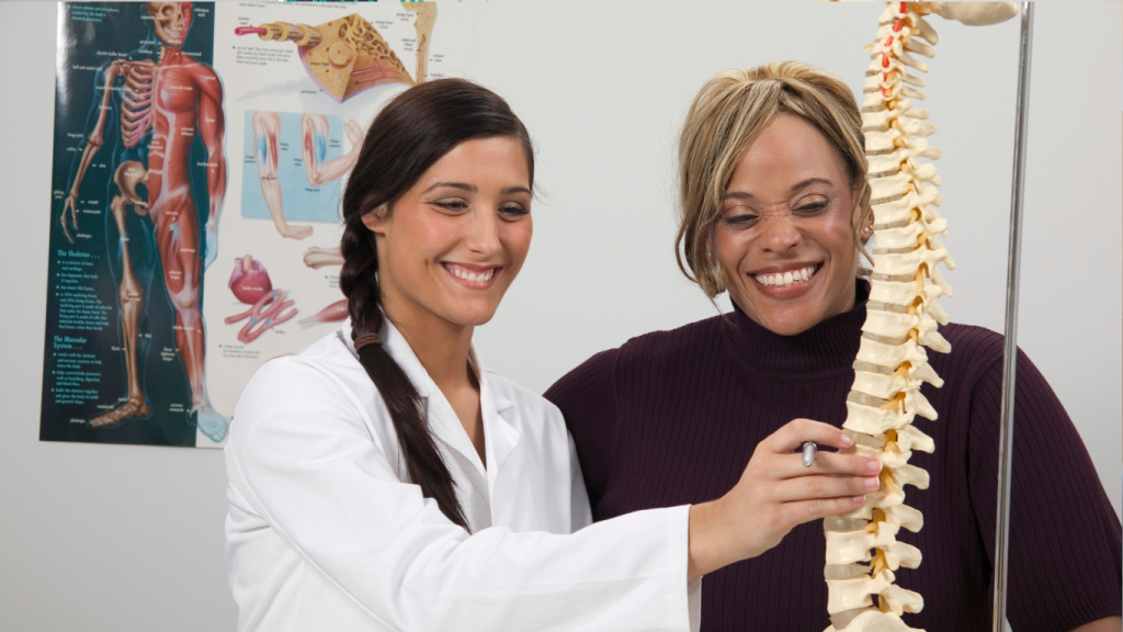 Chiropractor explaining the spine to a patient using a model during an office visit
