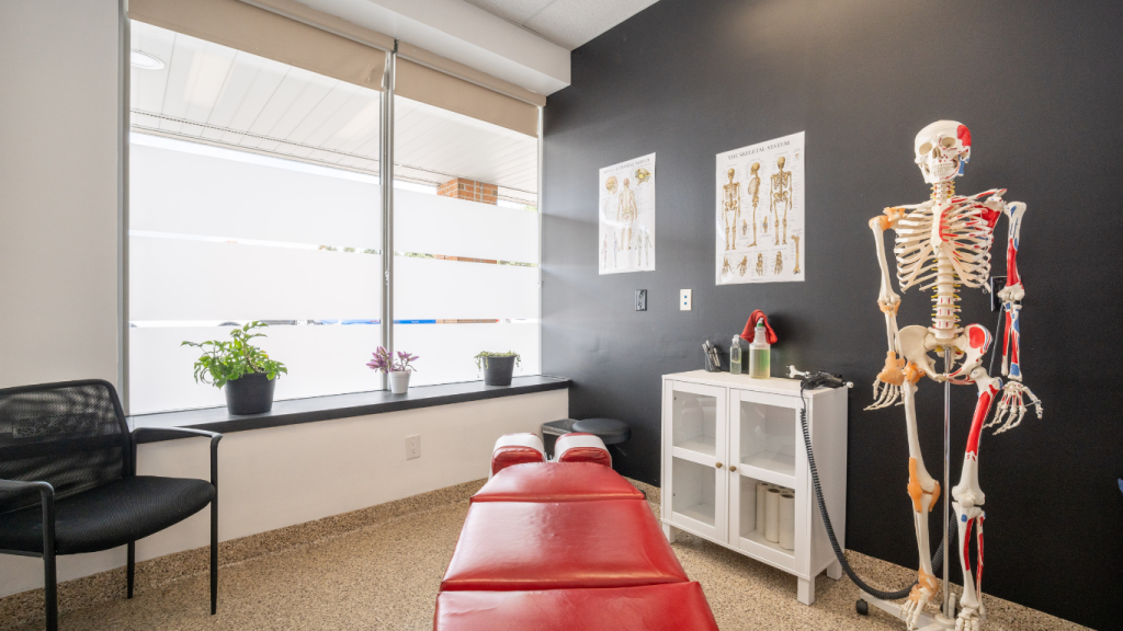 A professional photo of a modern chiropractic adjustment room, featuring a red table and an anatomical skeleton, used to build trust on a chiropractor's website.